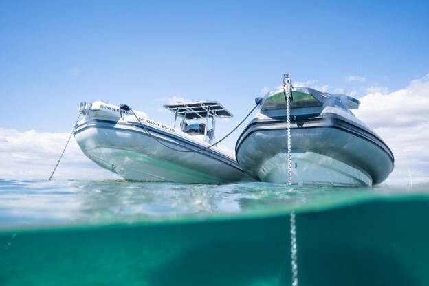 Rigid inflatable boats anchored on clear water near Alcudiamar marina in northern Mallorca.