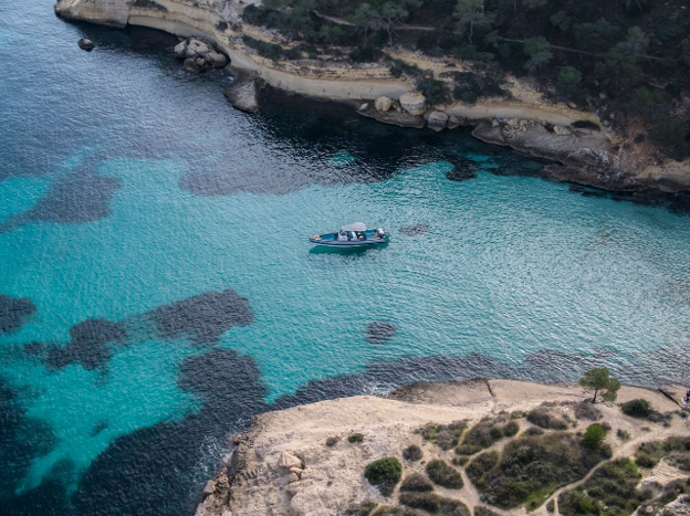Boat cruising in clear turquoise water near Marina de Bonaire, representing relaxed boating in northern Mallorca.